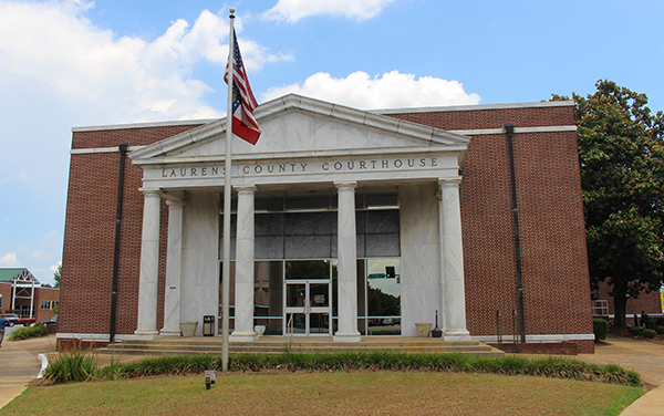 Front exterior of the Laurens County Courthouse with columns and an American flag in Dublin, Georgia
