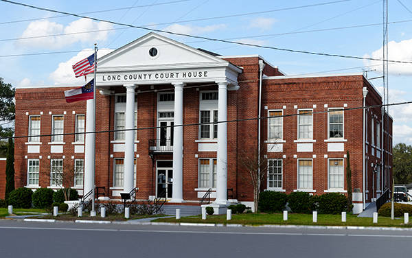 Historic Long County Courthouse with white columns and an American flag in Ludowici, Georgia
