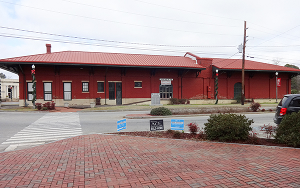 Historic red-brick Montezuma Depot beside a paved downtown plaza in Macon County, Georgia