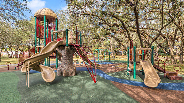 Nature-themed playground with tree-inspired play structures at Rolling Oaks Park in Miami Gardens, Florida