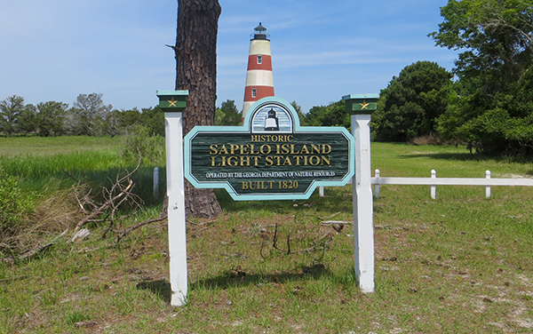 Historic Sapelo Island Lighthouse behind the entrance sign on Sapelo Island in McIntosh County, Georgia