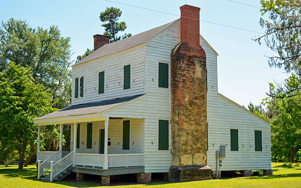 Historic Seaborn Goodall House with white siding, green shutters and brick chimneys in Screven County, Georgia
