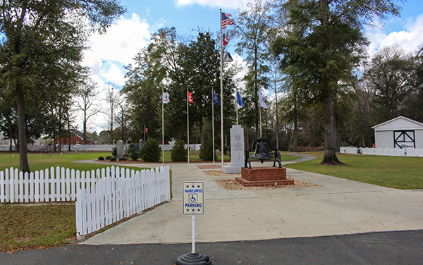 Veterans Memorial Park entrance with flags, bell monument and landscaped grounds in Reidsville, Georgia