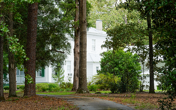 Historic white Wimberly Plantation House partly visible through trees in Twiggs County, Georgia
