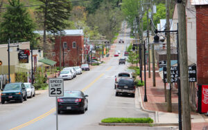 Downtown street with storefronts, parked cars, trees, and hillside road in the Ball Ground Historic District in Cherokee County, Georgia