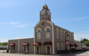 Historic Barnesville City Hall with a clock tower, arched windows, awnings, and decorative streetlights in Barnesville, Georgia.