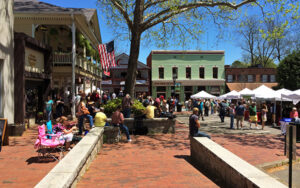 Visitors, market tents, historic storefronts, trees, and brick walkways at Dahlonega Public Square in Georgia.