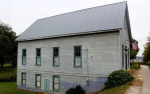 Historic wooden Demorest Woman’s Club building with a metal roof and American flag in Demorest, Georgia