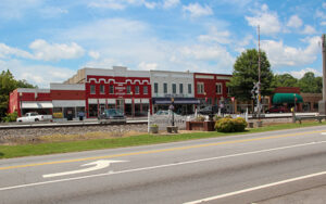 Historic storefronts, railroad tracks, landscaped public space, and roadway in downtown Tallapoosa, Georgia