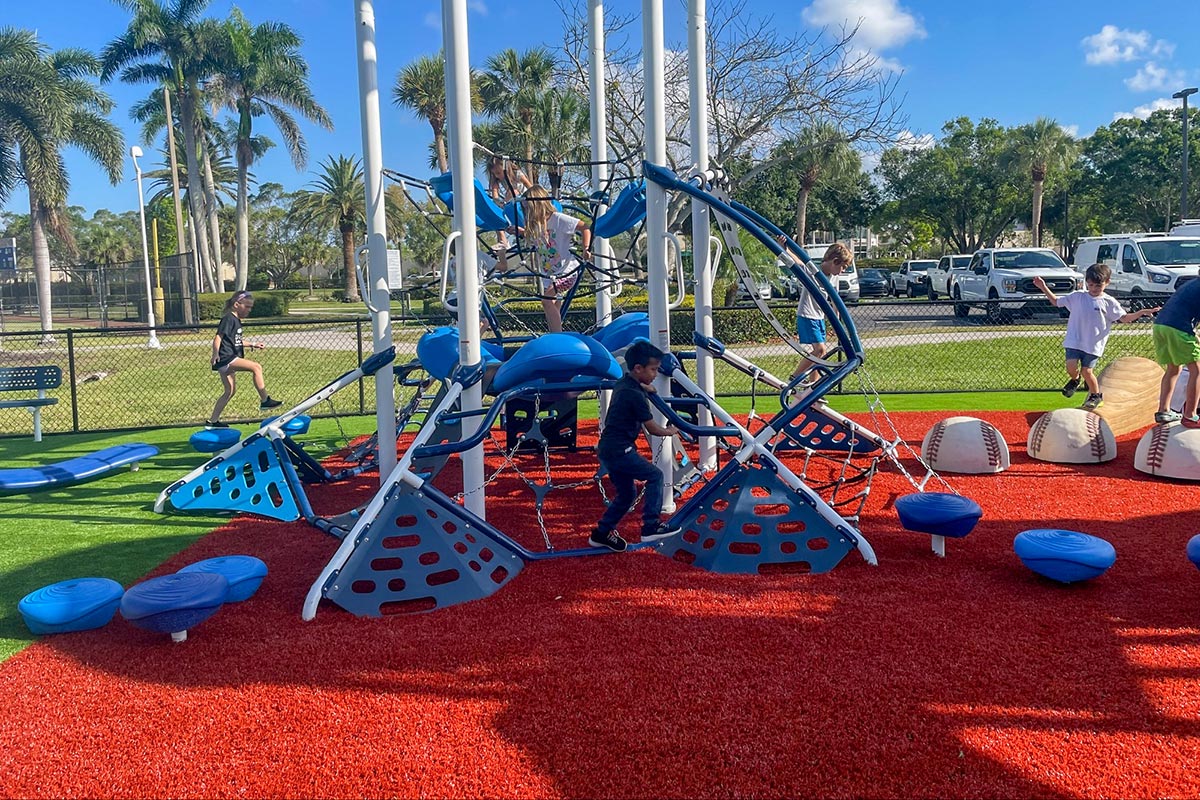 Children playing on red and green safety surfacing at Fleischmann Park in Naples, Florida