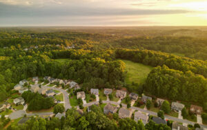 Aerial view of a Forsyth County, Georgia neighborhood with homes, roads, woodland, and open green space