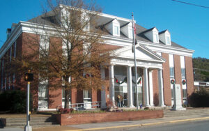 Brick Gordon County Courthouse with white columns, entrance steps, flagpole, and trees in Calhoun, Georgia