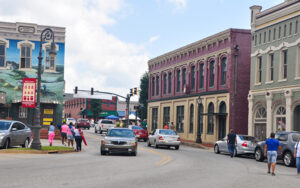 Historic storefronts, traffic, pedestrians, streetlights, and a painted mural in downtown Barnesville, Georgia.