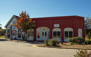 Historic brick Hoschton City Hall building with storefront-style entrances and landscaped streetscape in Hoschton, Georgia.