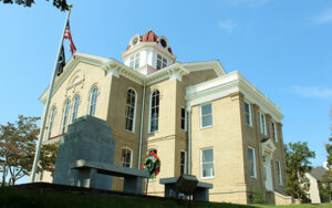 Historic Jackson County Courthouse with a war memorial and flagpoles in Jefferson, Georgia.