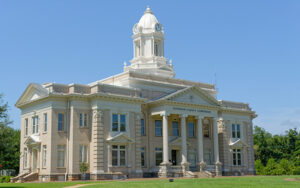 Historic Jefferson County Courthouse with a clock tower, columns, and landscaped lawn in Louisville, Georgia.