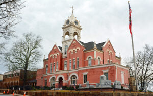 Historic red-brick Jones County Courthouse with a clock tower, flagpole, and memorials in Gray, Georgia.