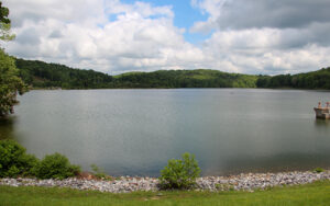 Lake Zwerner with a tree-lined shoreline, rocky bank, and cloudy sky in Lumpkin County, Georgia.