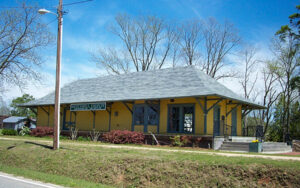 Yellow former railroad depot with covered platform in downtown Mitchell, Georgia