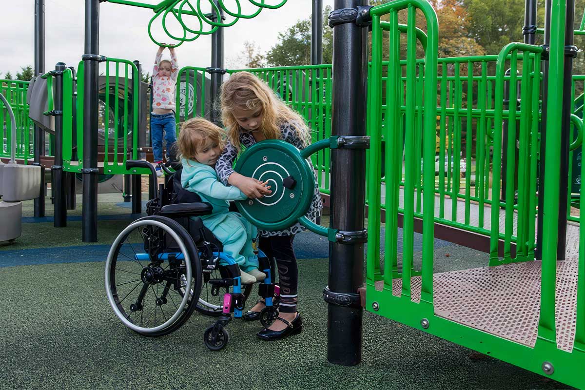 Child using a wheelchair interacting with a sensory play panel at Riverview Park in Chattanooga, Tennessee