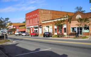 Historic brick storefronts, sidewalks, benches, street trees, and parked vehicles in downtown Sparta, Georgia