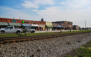 Railroad tracks beside historic storefronts and parked vehicles along Tallapoosa Street in downtown Bremen, Georgia
