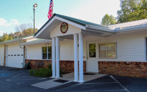 Waleska City Hall building with white columns, brick base, flagpole, and accessible parking spaces in Cherokee County, Georgia